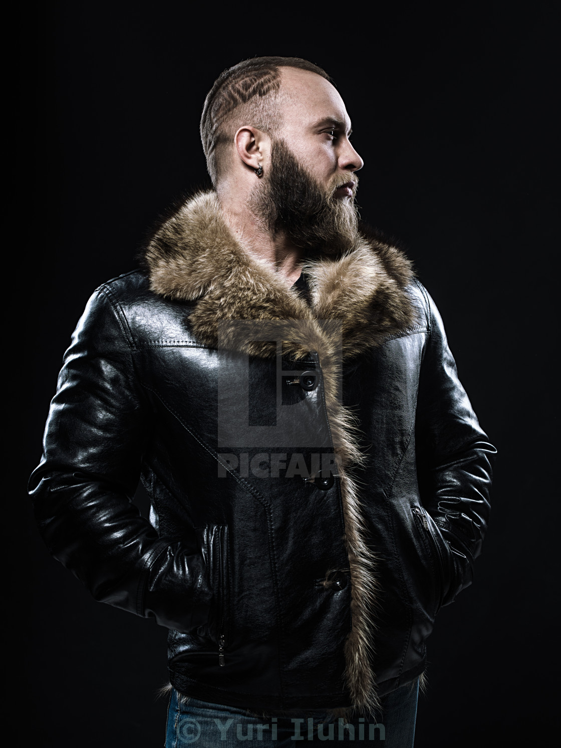 Brutal Handsome Unshaven Man With Long Beard And Moustache In Black Fur Coat With Collar